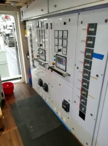 Control panel with electrical monitoring systems on a yacht, showcasing various gauges and switches for managing marine electrical services and automation.