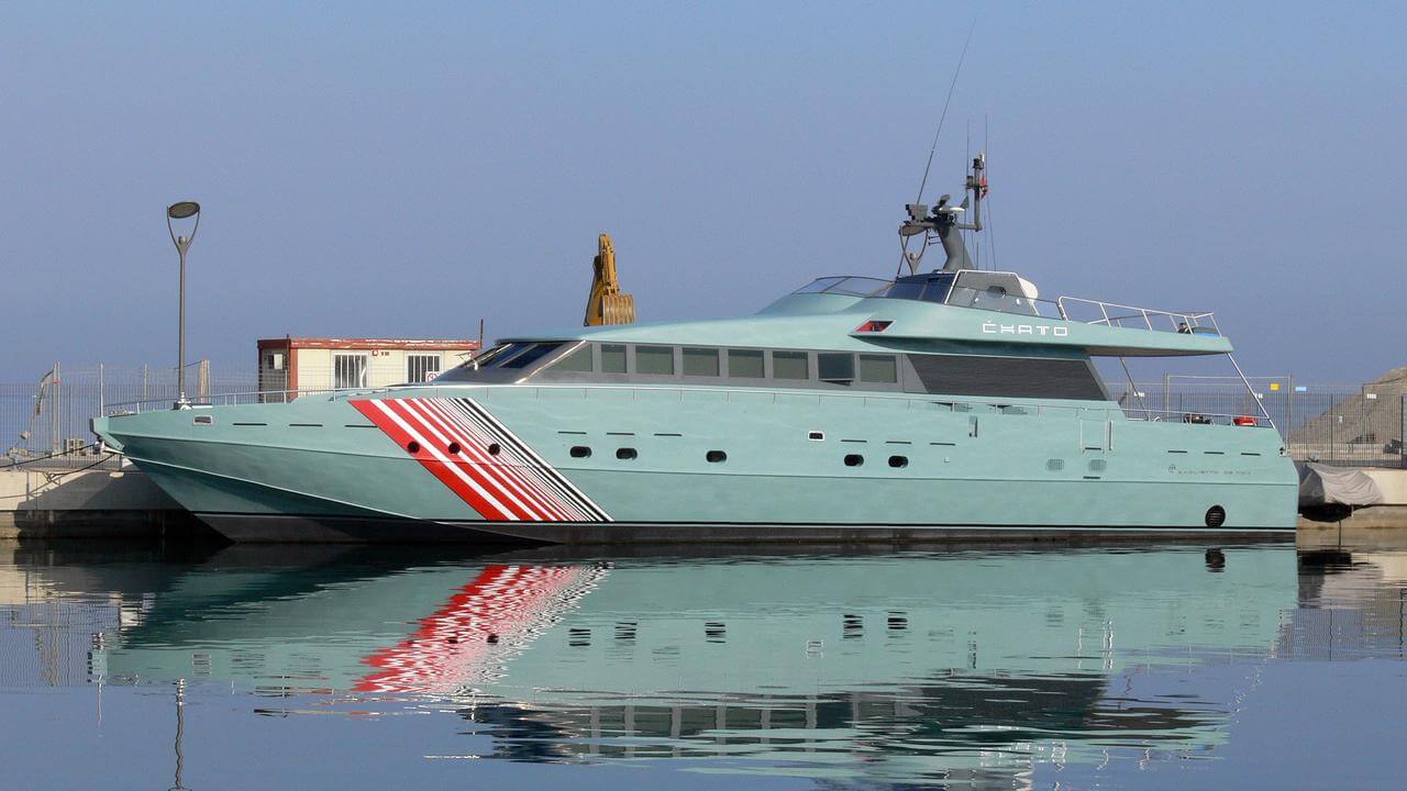 Chato yacht docked in calm waters, showcasing its sleek turquoise hull and distinctive red and white stripes, symbolizing speed and luxury in the yacht industry.