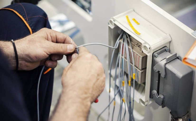 Technician connecting marine electrical wires to a control panel, illustrating marine electrical services and installations for boats and yachts.