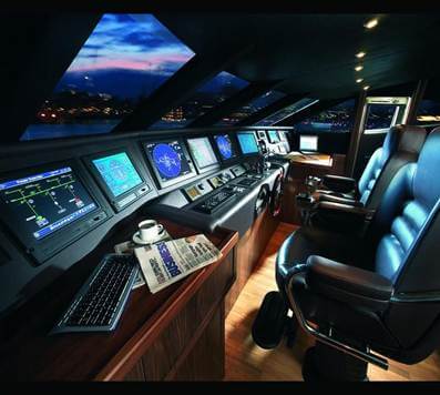Interior view of a modern marine bridge showcasing multiple digital displays, control panels, and a comfortable chair, emphasizing advanced alarm monitoring systems for marine applications.