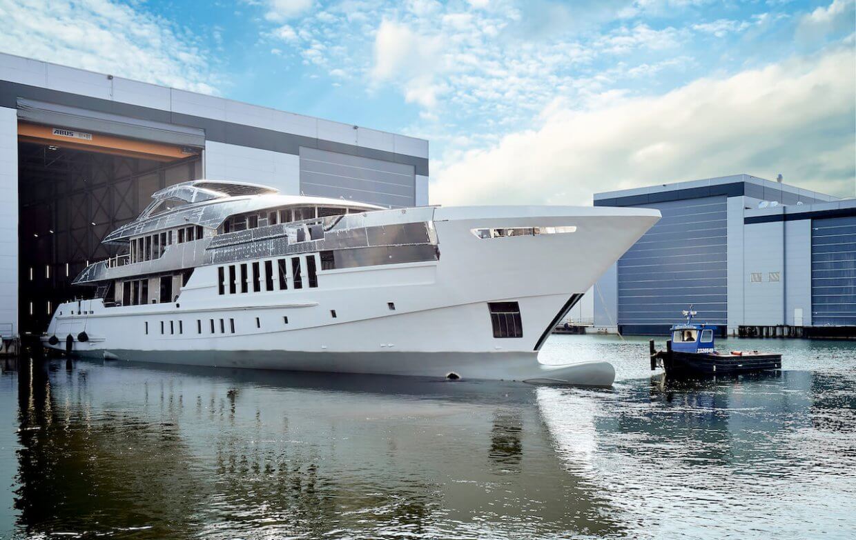 Luxury yacht emerging from the dock with modern design features and surrounding industrial backdrop, illustrating advanced marine technology and automation services by Tess Electrical LLC.