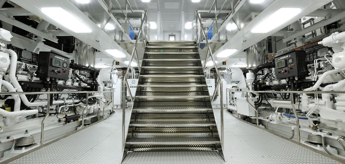 Marine engine room with metallic staircase, advanced machinery, and electrical control panels, highlighting Tess Electrical's expertise in marine engineering and electrical services for yachts.