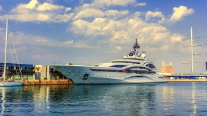 Luxury yacht docked at marina with clear blue sky and clouds, representing boating lifestyle and marine experiences.