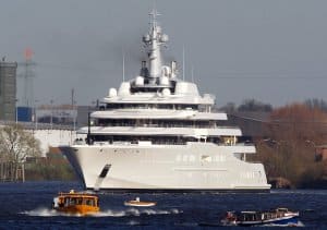 Luxury yacht navigating a waterway with smaller boats nearby, illustrating high-end marine vessels in the context of yacht upgrades and destinations.
