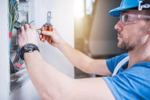 Electrician working on marine electrical systems, handling wires and tools, emphasizing expertise in yacht and marina electrical services.