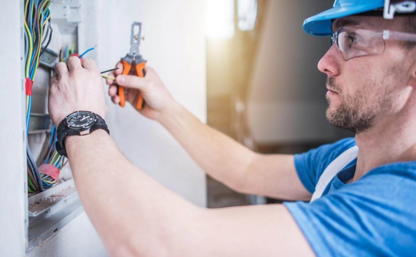 Electrician working on marine electrical systems, using tools to connect wires in a control panel, emphasizing expertise in yacht electrical services.