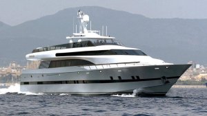 Luxury yacht cruising on water with mountains in the background, showcasing marine engineering and design relevant to yacht maintenance and electrical systems.