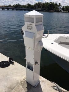 Marina power pedestal with electrical outlets and a water connection beside a boat dock, reflecting Tess Electrical LLC's marine electrical services.