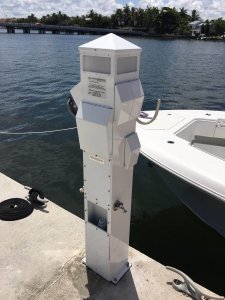 Pedestal electrical station installed at Grove Isle Marina, Miami, showcasing marine electrical services by Tess Electrical LLC, with a boat docked nearby.