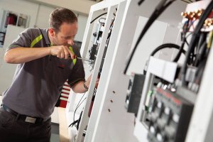 Technician working on marine electrical systems in a workshop, highlighting expertise in yacht maintenance and electrical services.