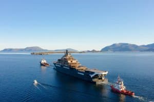 Largest yacht in the world navigating calm waters, accompanied by smaller support vessels, showcasing marine engineering and luxury design.