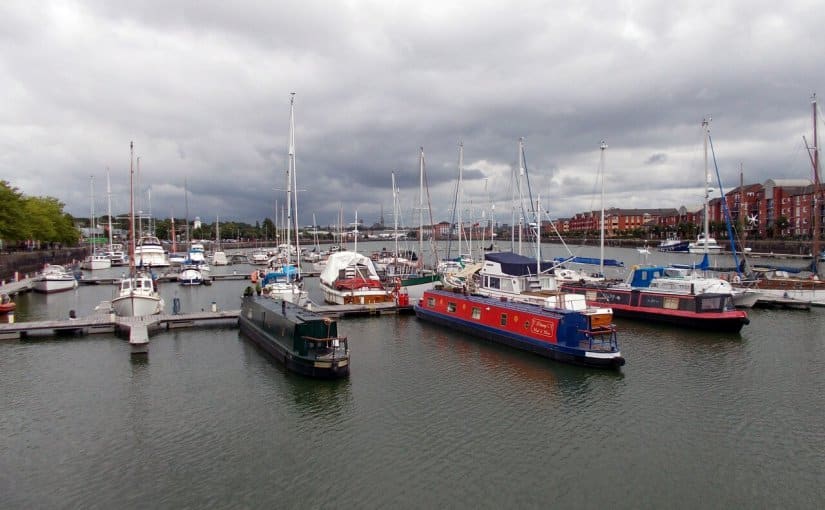 Marina with various boats docked in calm water under a cloudy sky, illustrating potential storm impact on marina operations and electrical equipment.