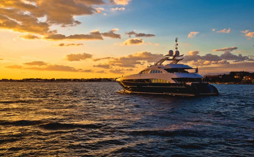 Luxury yacht sailing at sunset, showcasing complex marine electrical systems and engineering in a serene waterfront setting.
