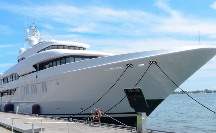 Luxury yacht docked by the waterfront, showcasing sleek design and modern features, relevant to yacht surveys and maintenance services.