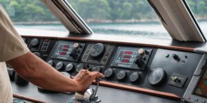 Yacht control panel with gauges and a hand operating the throttle, illustrating marine power management systems for enhanced performance and efficiency.