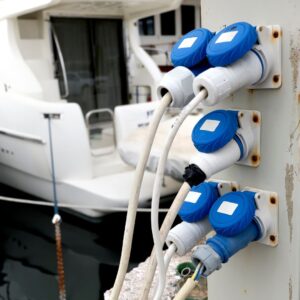 Yacht electrical outlets and cables at a marina, illustrating essential components for yacht electrical services and safety protocols.