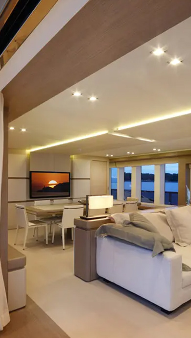 img cantalupi 01 Modern yacht interior featuring LED lighting, elegant furniture, and a sunset view through large windows, showcasing energy-efficient design.