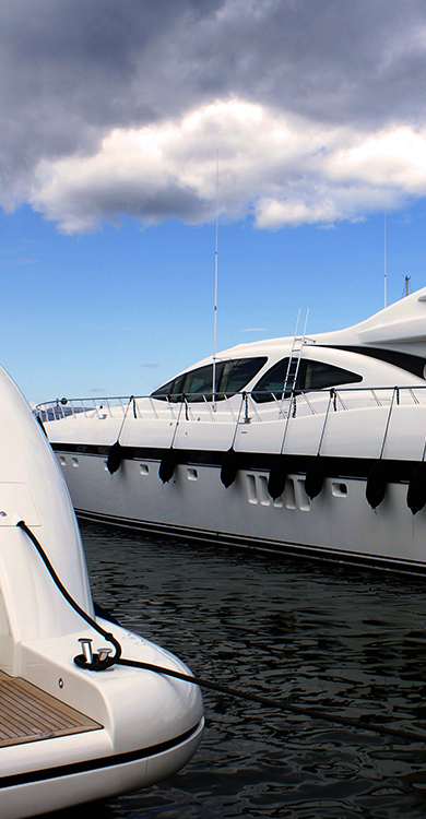 Luxury yachts docked in a marina under a cloudy sky, showcasing sleek designs and high-quality materials relevant to Cantalupi lighting solutions for marine vessels.