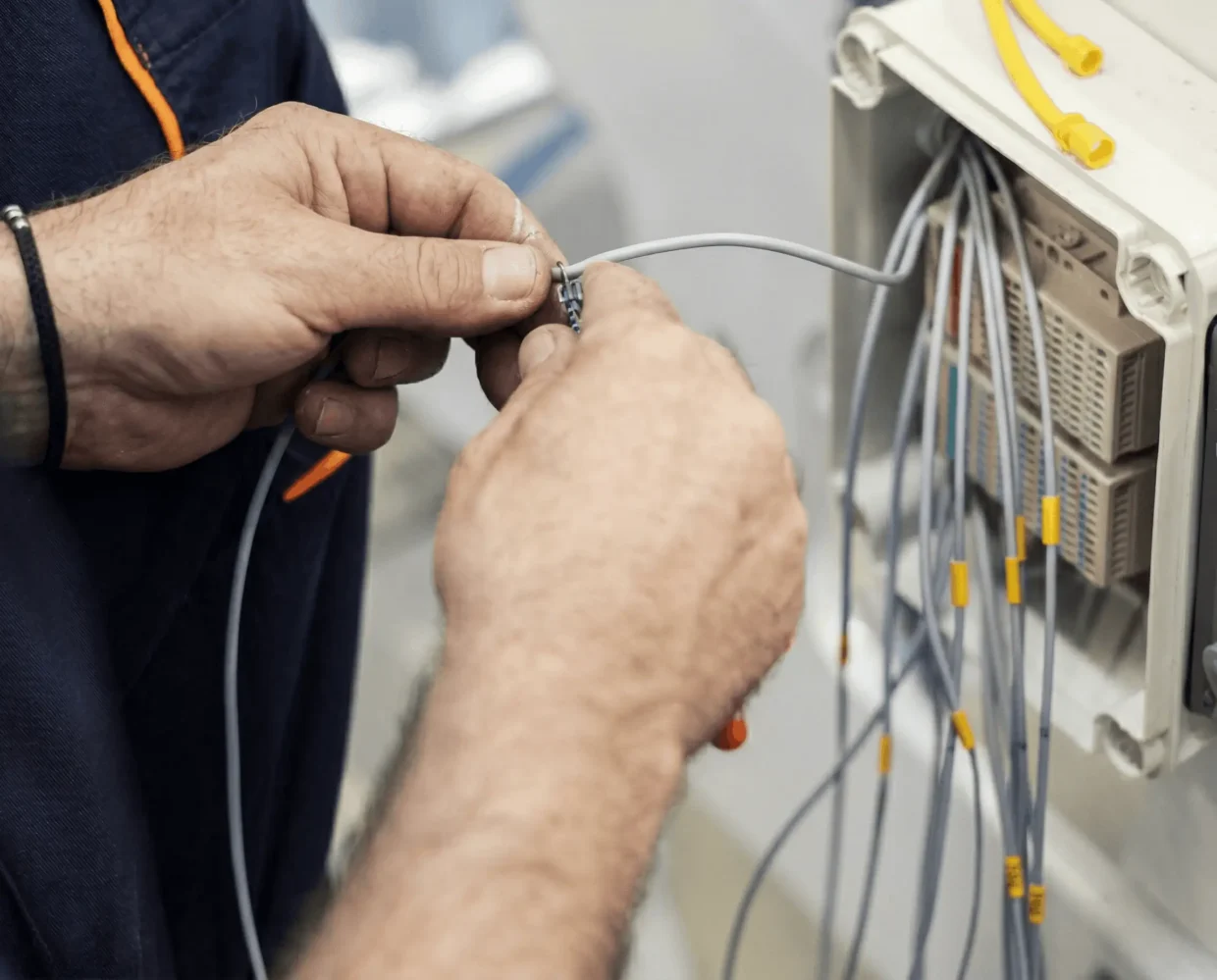 Hands connecting wires to a marine electrical system, showcasing expertise in yacht electrical installations and maintenance.