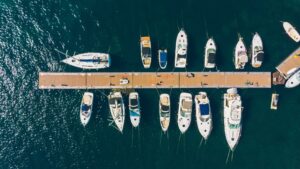 Aerial view of a marina with multiple yachts docked alongside a wooden pier, highlighting luxury yacht maintenance and marine services.