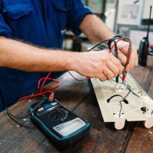 Technician using a multimeter to test electrical connections on a yacht component, emphasizing marine electrical maintenance and installation services.