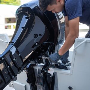 Person performing maintenance on a yacht's outboard engine, emphasizing the importance of regular engine care for safety and efficiency.