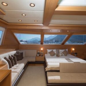 Luxurious yacht interior featuring a spacious seating area, elegant bedding, and large windows with scenic views, emphasizing the importance of regular interior cleaning and maintenance for yacht owners.