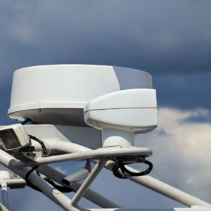 Yacht security alarm system components on boat mast against cloudy sky.
