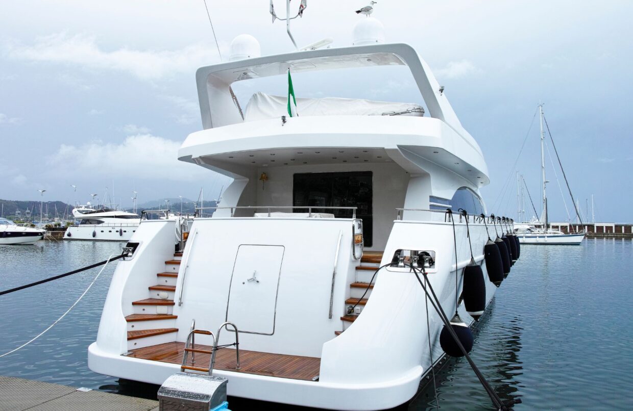 Luxury yacht docked at marina with wooden steps, fenders, and a cloudy sky, representing TESS LLC's marine electrical services at Safe Harbor Savannah Yacht Center.