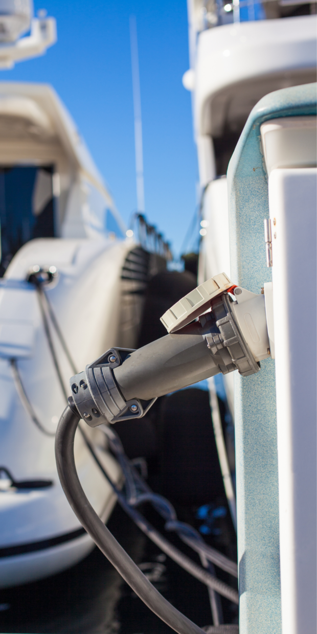 Electrical connection on a yacht docked in Dade County, showcasing a power inlet and cable, emphasizing marine electrical services offered by TESS LLC.