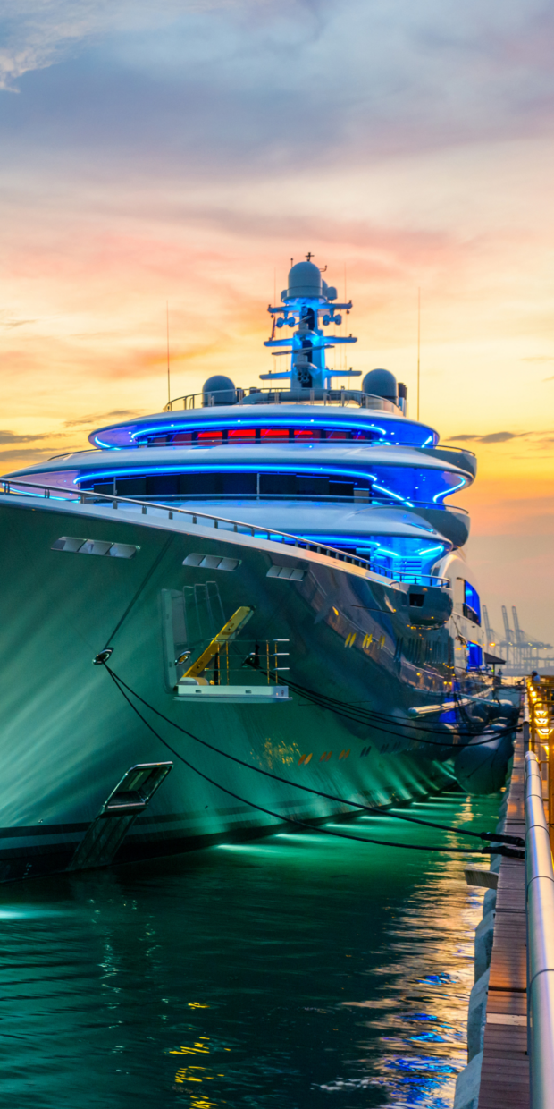 Luxury yacht illuminated with blue lights docked at sunset, showcasing advanced marine electrical features relevant to yacht services in Dade County.