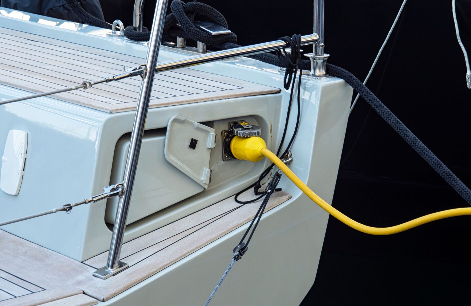 Yacht electrical connection with yellow power cord plugged into shore power inlet, highlighting marine electrical services for yacht owners in Dade County.
