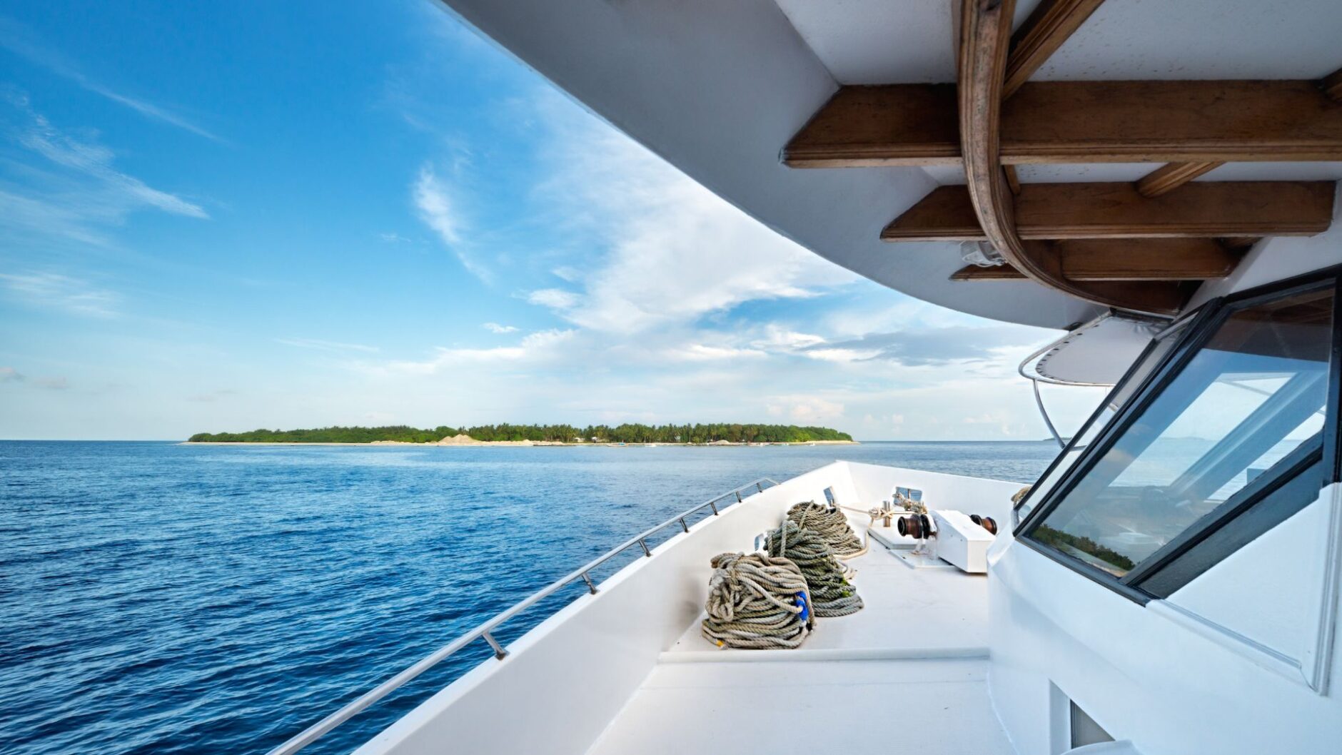 Yacht deck view with ropes and shoreline of an island in Broward County, highlighting marine services and yacht maintenance.