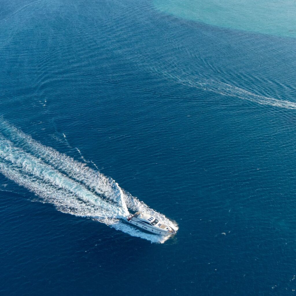 Luxury yacht cruising through deep blue waters, leaving a wake, emphasizing the importance of yacht security systems for safety and theft prevention.