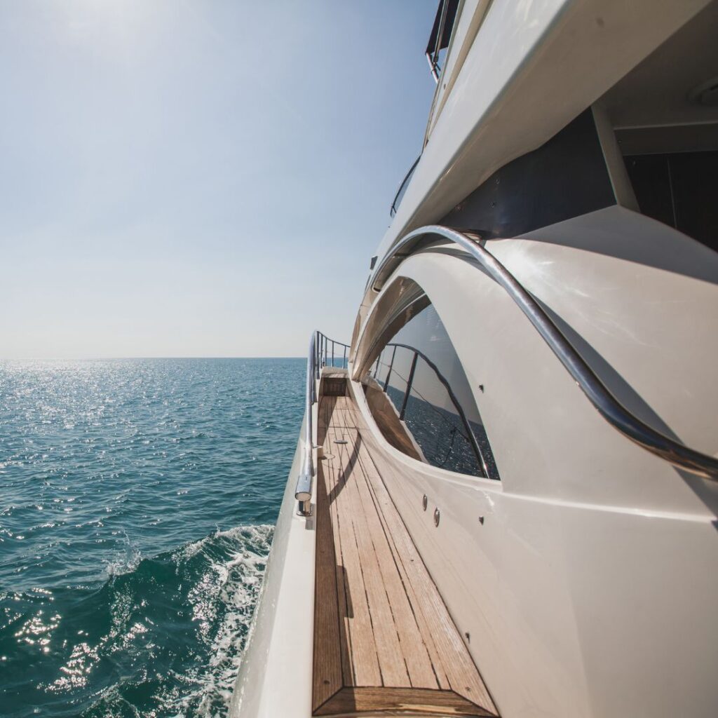 Luxury yacht cruising on clear blue waters, showcasing sleek design and polished wooden deck, representing the boating lifestyle highlighted in upcoming September boat shows.