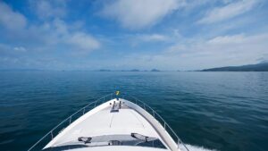 Boat bow cutting through calm waters under a blue sky, symbolizing marine exploration and yachting adventures.