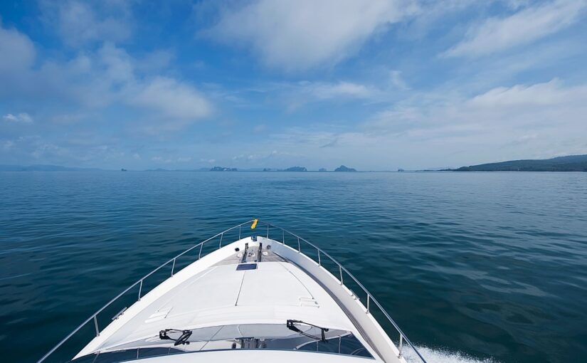 Yacht bow navigating calm waters under a clear blue sky, representing marine services and maintenance.