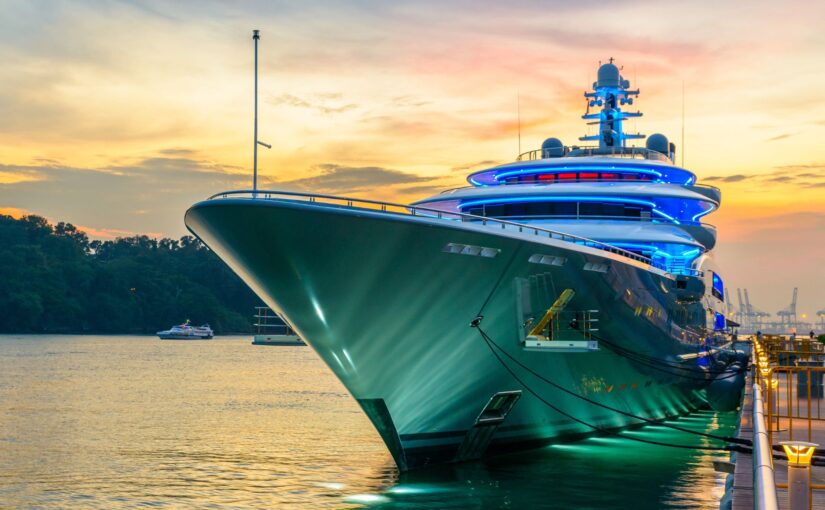 Luxury yacht illuminated at sunset, showcasing sleek design and advanced marine technology, relevant to upcoming boat shows and Tess LLC's marine electrical services.