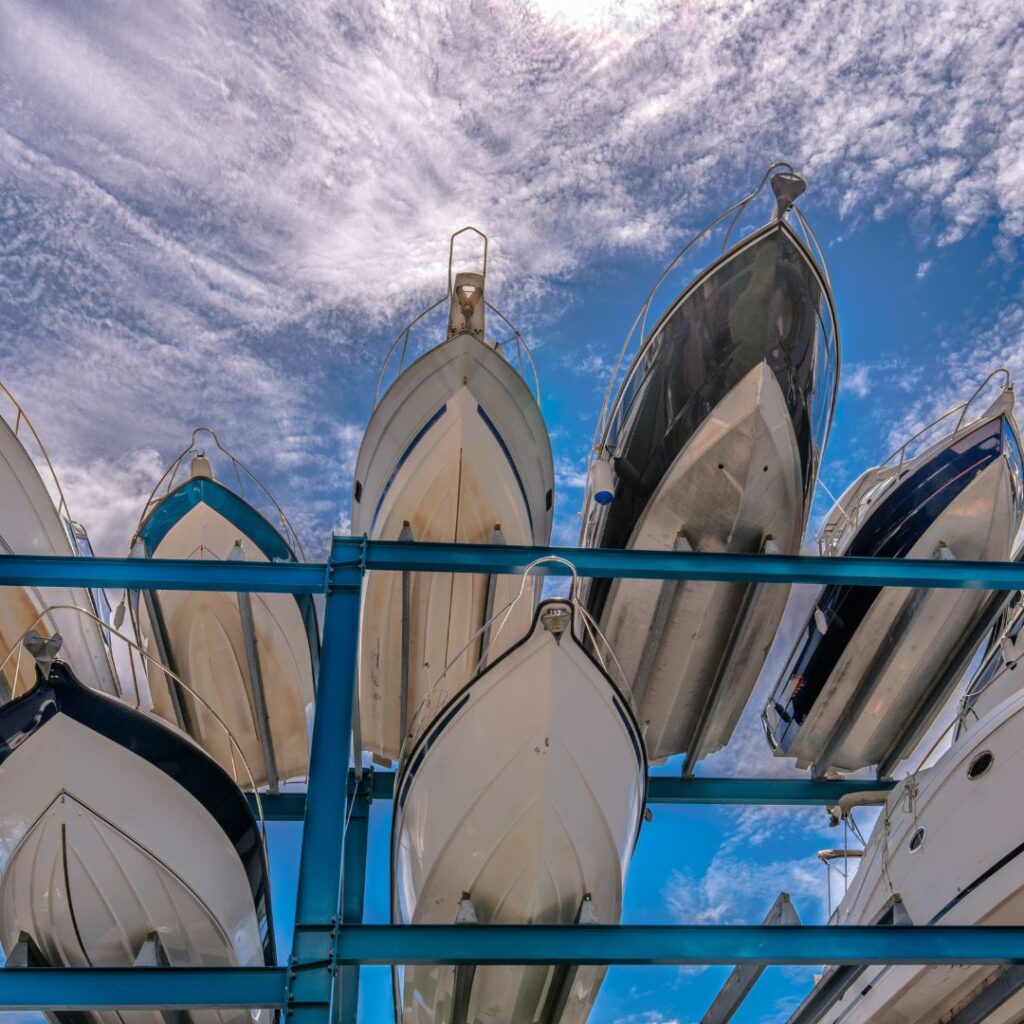 Boats stacked on a storage rack under a blue sky with clouds, representing marine equipment relevant to marine repair services.