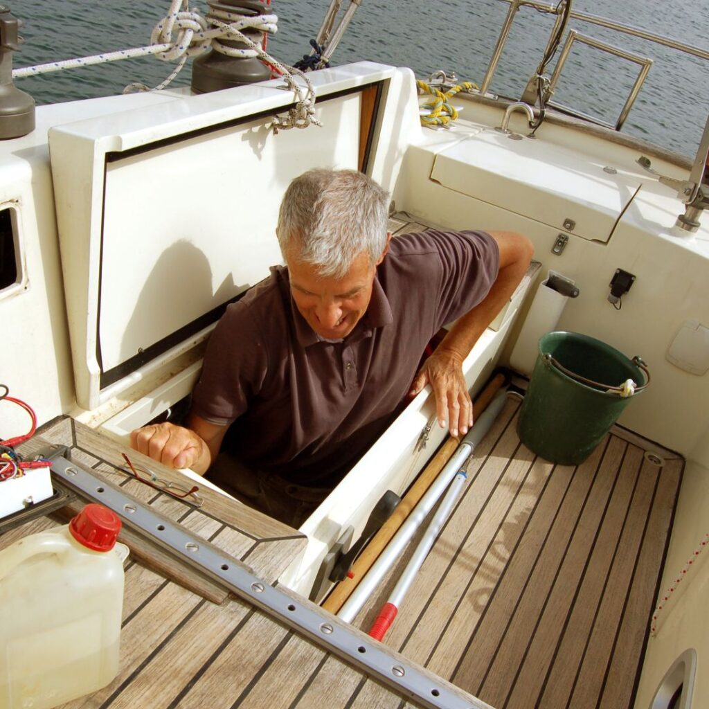 Man inspecting marine equipment inside a boat compartment, emphasizing hands-on repair and maintenance expertise relevant to marine repair services.