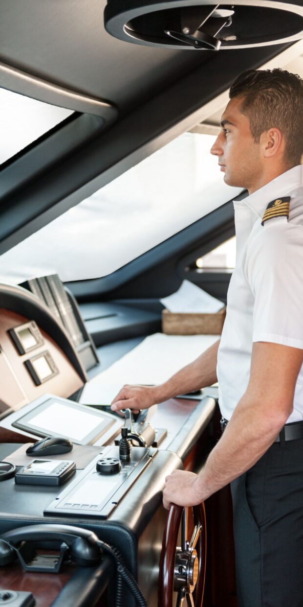 3 yacht electrical services in palm beach county Yacht captain operating navigation controls in a modern yacht's cockpit, showcasing advanced marine electrical technology and systems.