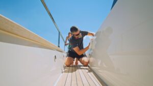 Person performing maintenance on a yacht's exterior, showcasing attention to detail in marine care and upkeep.