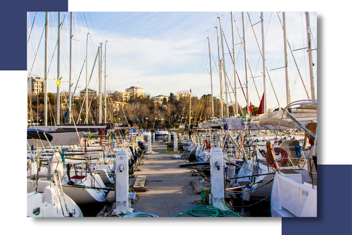Marina scene with yachts docked at a pier, showcasing electrical power connections and masts, representing TESS LLC's marine electrical services for yachts.