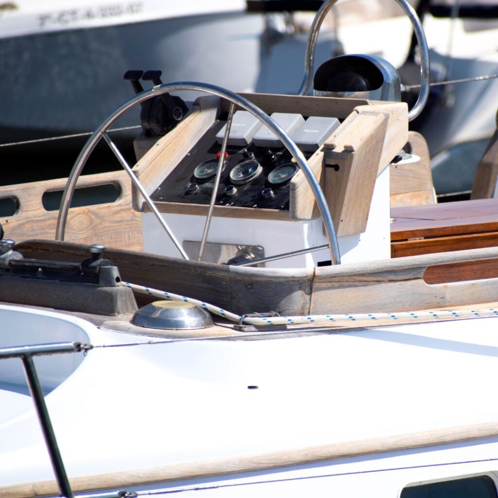 Yacht helm featuring control panel with gauges, switches, and steering wheel, illustrating marine electrical systems relevant to yacht refits and maintenance in South Florida.