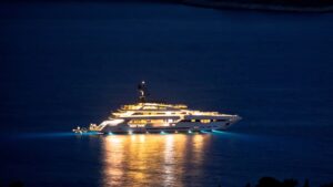 Luxurious yacht illuminated at night on calm waters, showcasing advanced lighting and design, relevant to yacht security and power management discussions by TESS LLC.