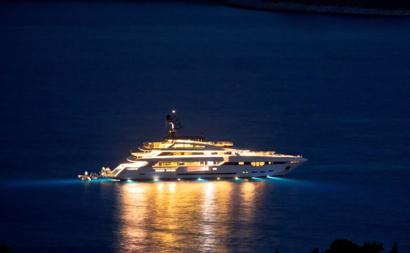 Luxury yacht illuminated at night, showcasing advanced power management systems and energy efficiency in a marine setting.