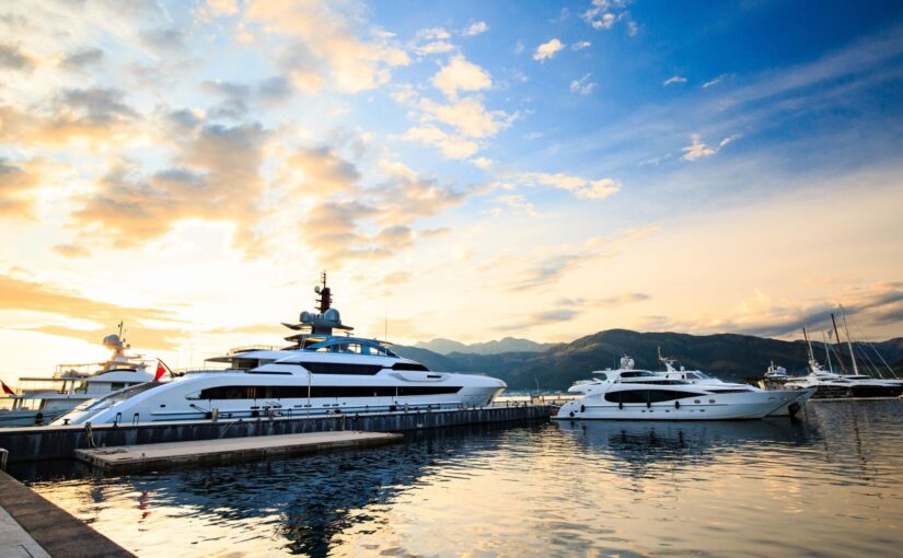 Luxury yachts docked at sunset in a marina, showcasing marine security and maintenance importance for yacht alarm systems.