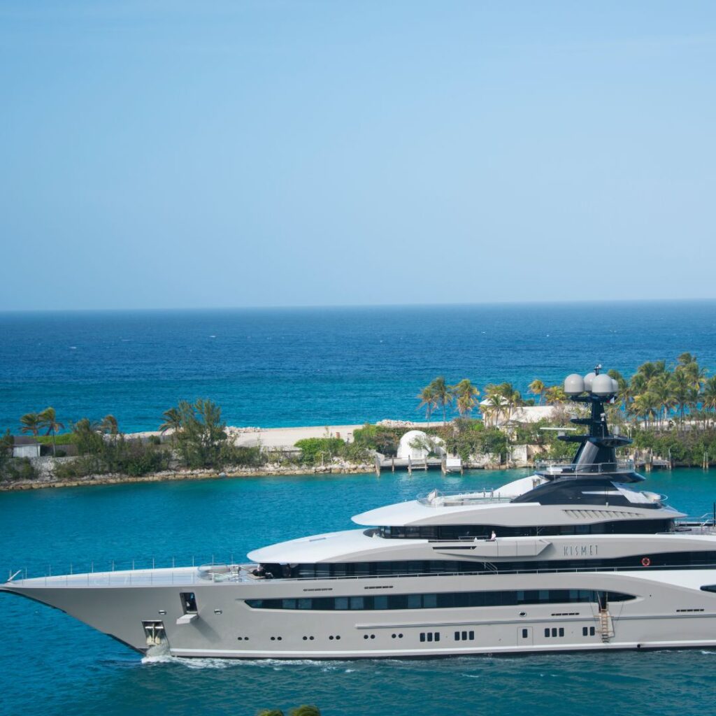 Luxury yacht navigating turquoise waters near a sandy beach in South Florida, emphasizing marine security and maintenance for optimal performance.