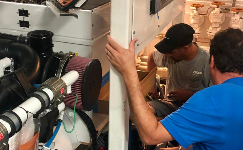 Technicians from TESS LLC performing maintenance on a yacht's power system, showcasing advanced marine electrical components and installation processes.
