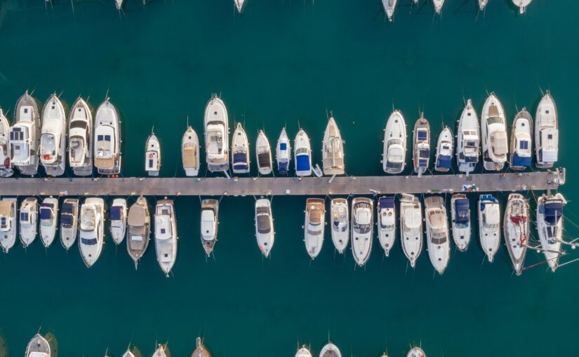 Aerial view of a marina filled with various boats and yachts docked along a wooden pier, showcasing TESS LLC's marine repair services for vessels in Southern Florida.